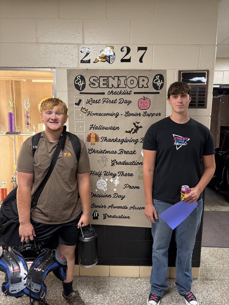 students posing next to banner