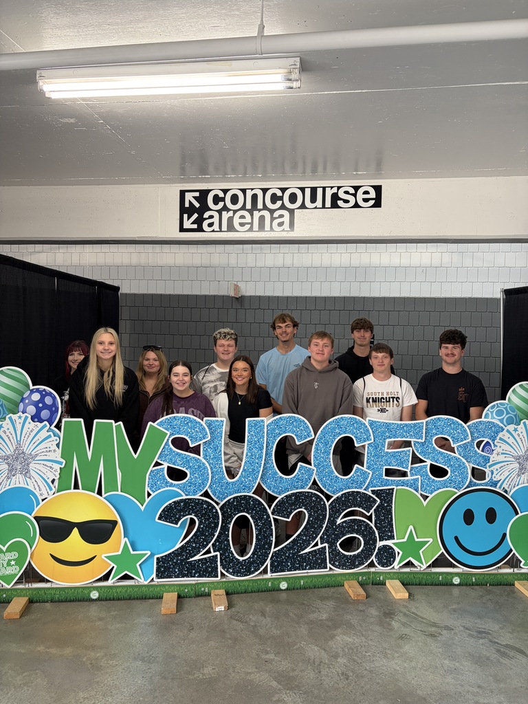 student posing next to banner