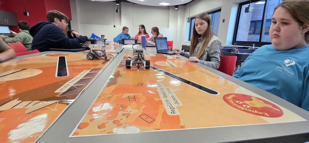 Students look on as their robot travels based on the code they wrote for it.