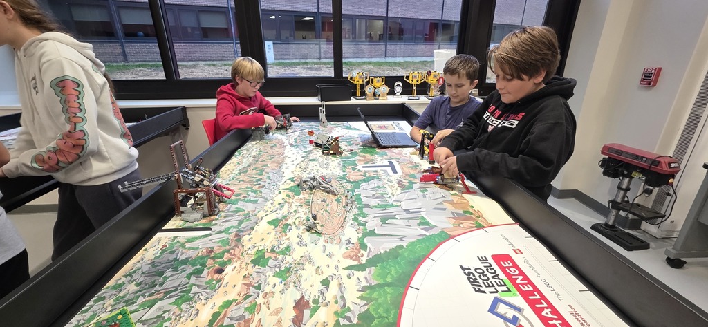 Middle schoolers for on their lego robot at the high top table