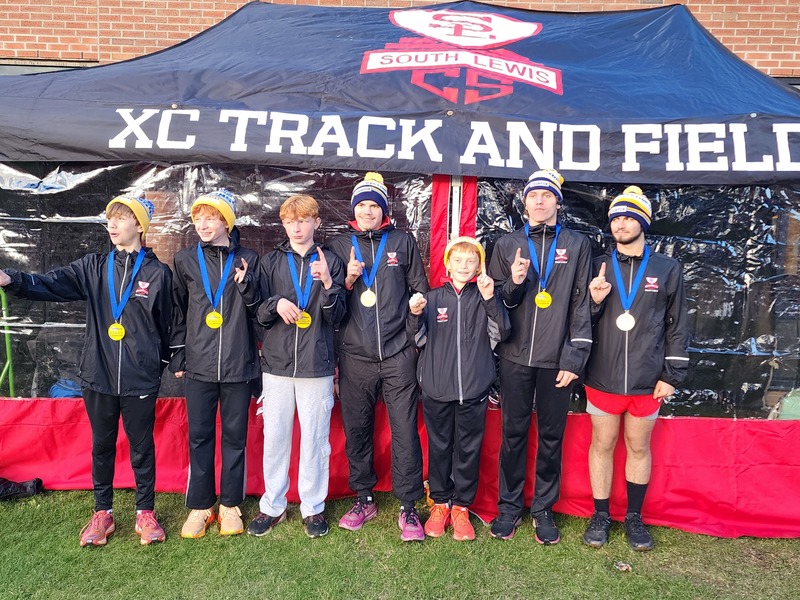 Cross Country boys team standing at tent wearing their medals