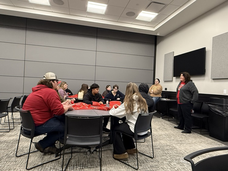 students sitting at tables, presenter talking up front 