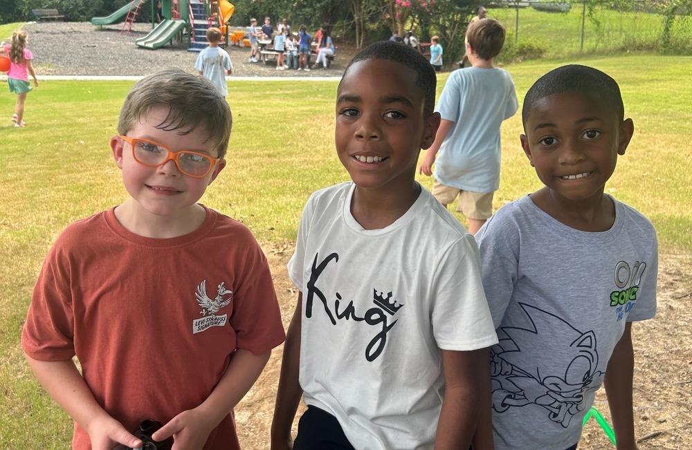 3 elementary boys standing on a playground