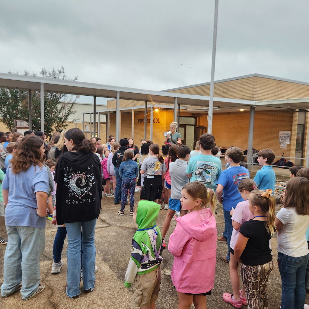 Elementary and junior high students gather outside of a school building