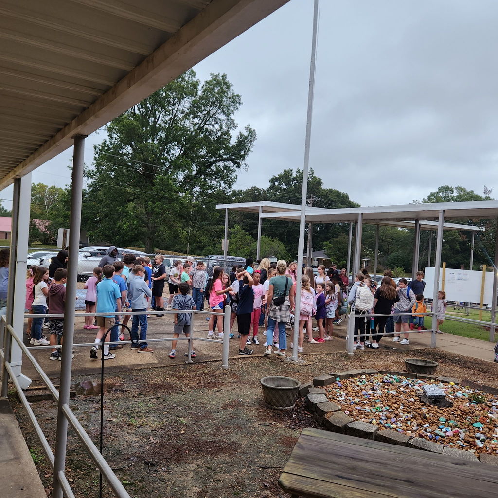 Elementary and junior high students gather outside of a school building