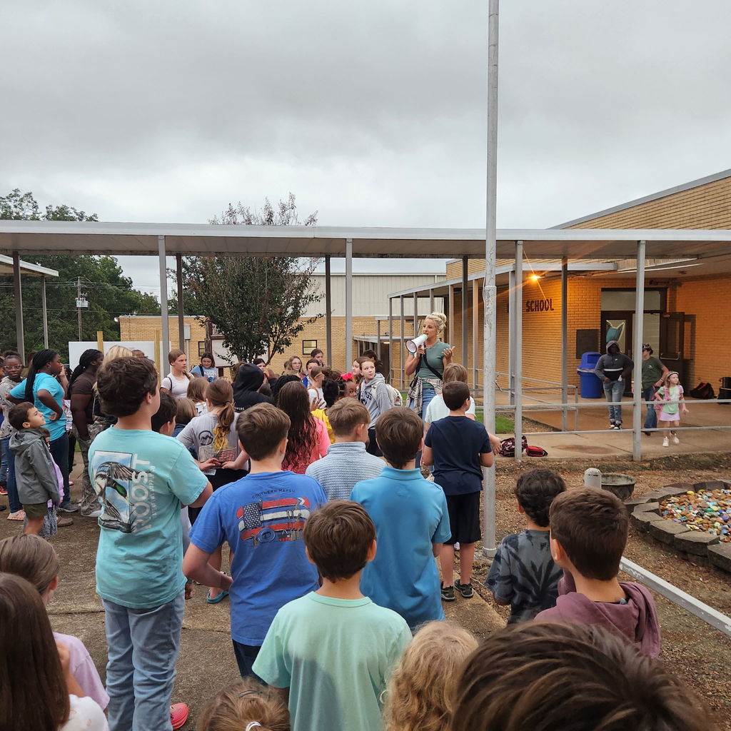 Elementary and junior high students gather outside of a school building