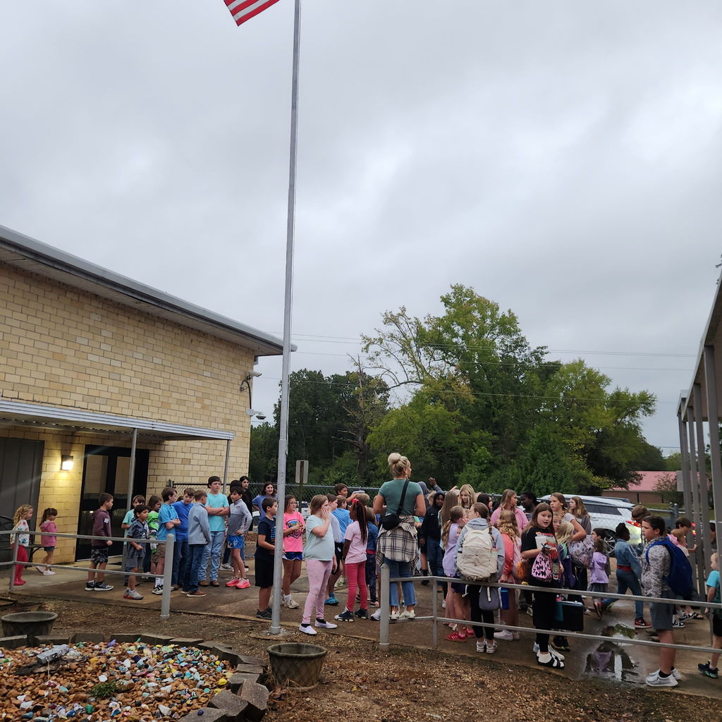 Elementary and junior high students gather outside of a school building