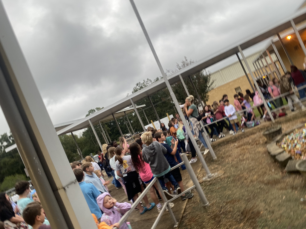 Elementary and junior high students gather outside of a school building