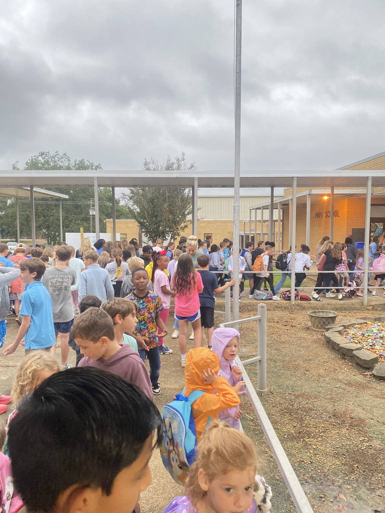 Elementary and junior high students gather outside of a school building