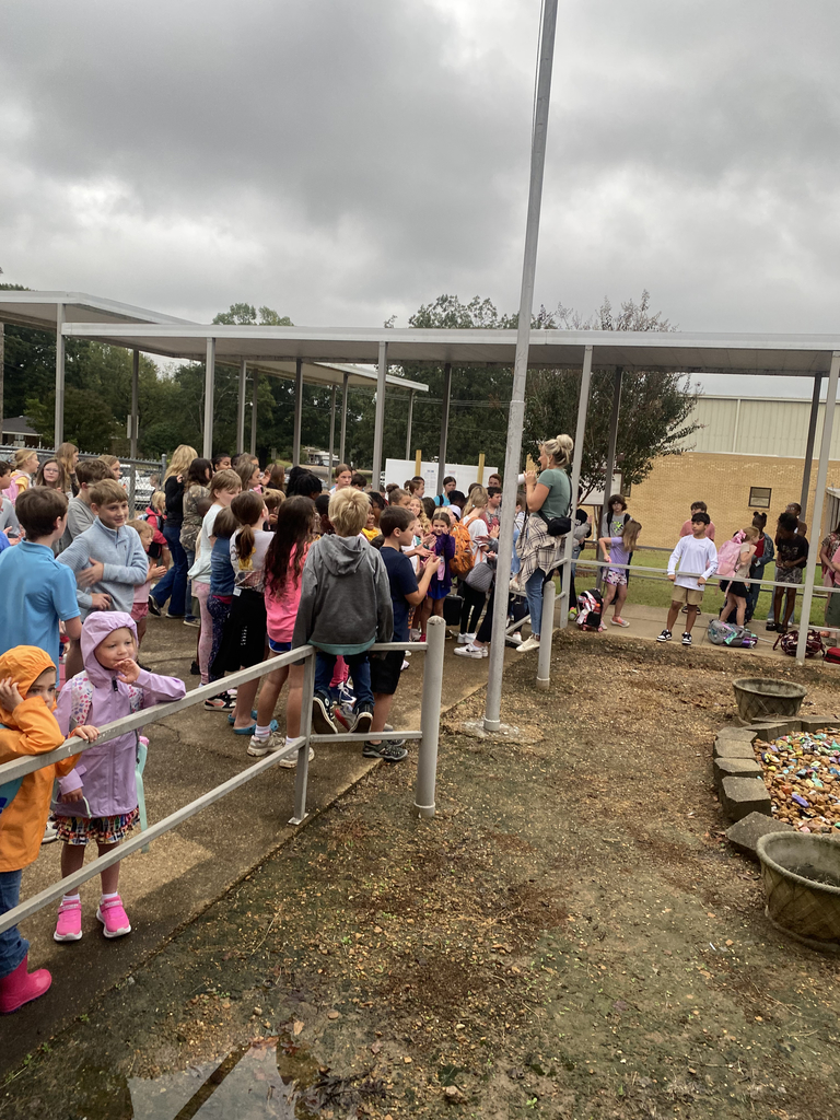 Elementary and junior high students gather outside of a school building