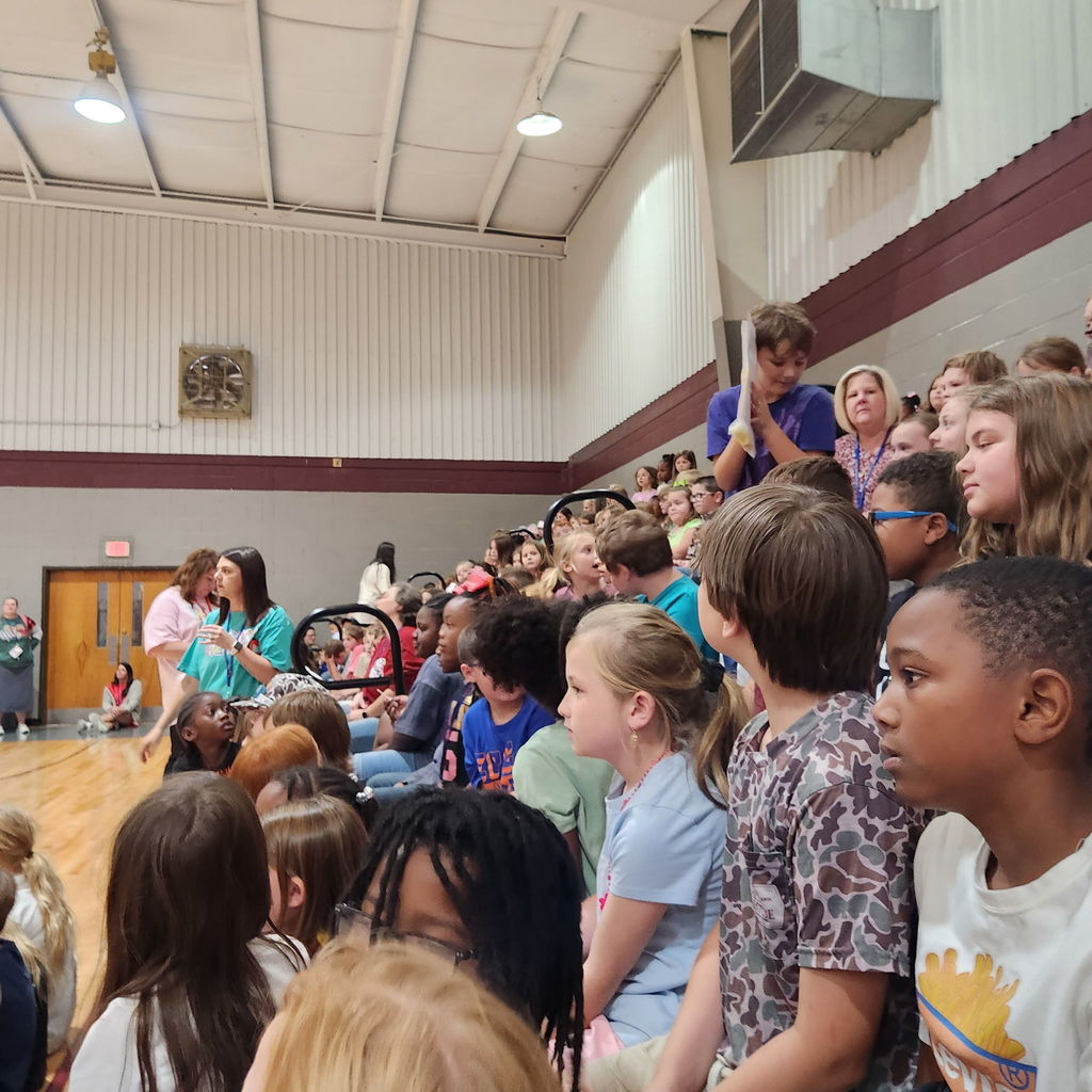 students in gymnasium stands at a pep rally