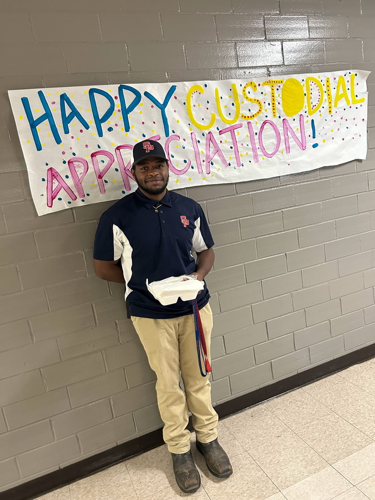 custodians standing in front of a sign