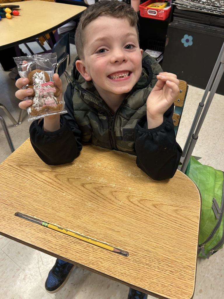 first grade students holding gingerbread men cookies
