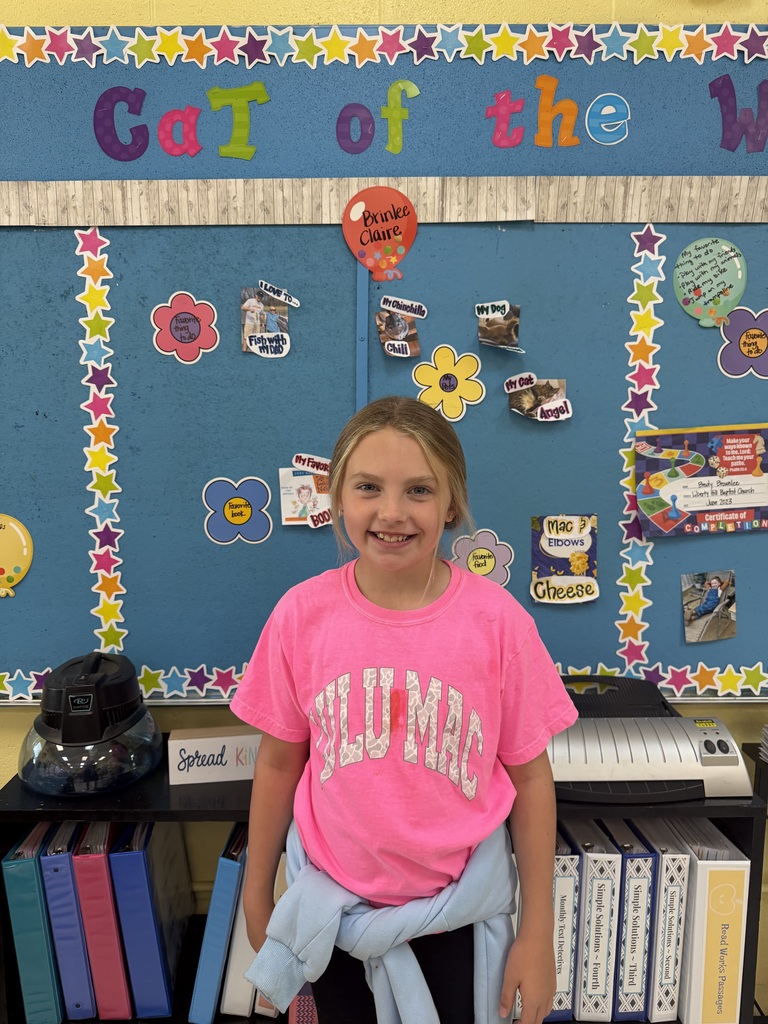 4th grade students standing in front of bulletin board