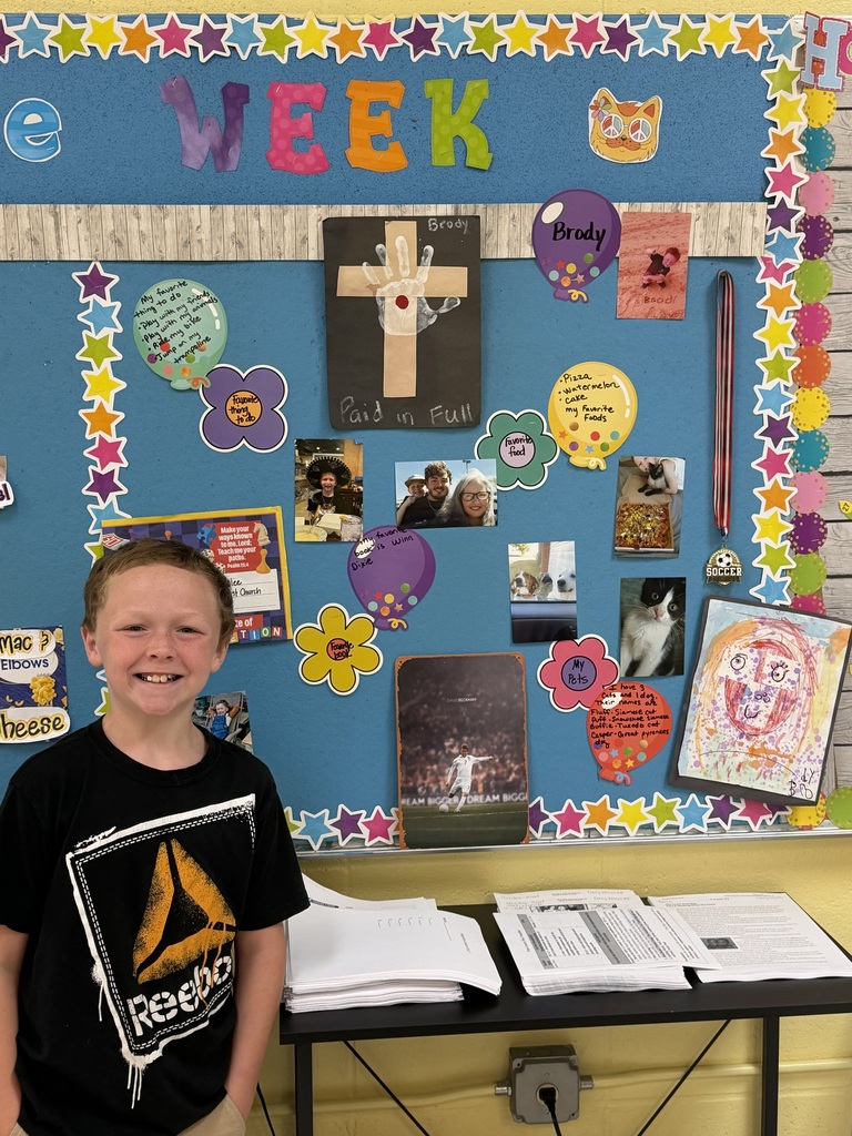 4th grade students standing in front of bulletin board