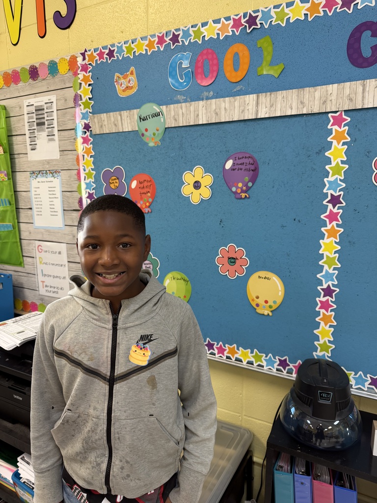 4th grade students standing in front of bulletin board