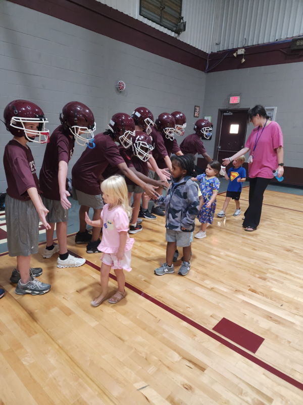 PreK students high fiving football players