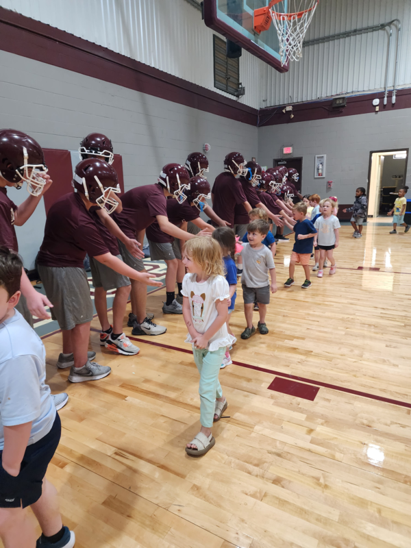 PreK students high fiving football players