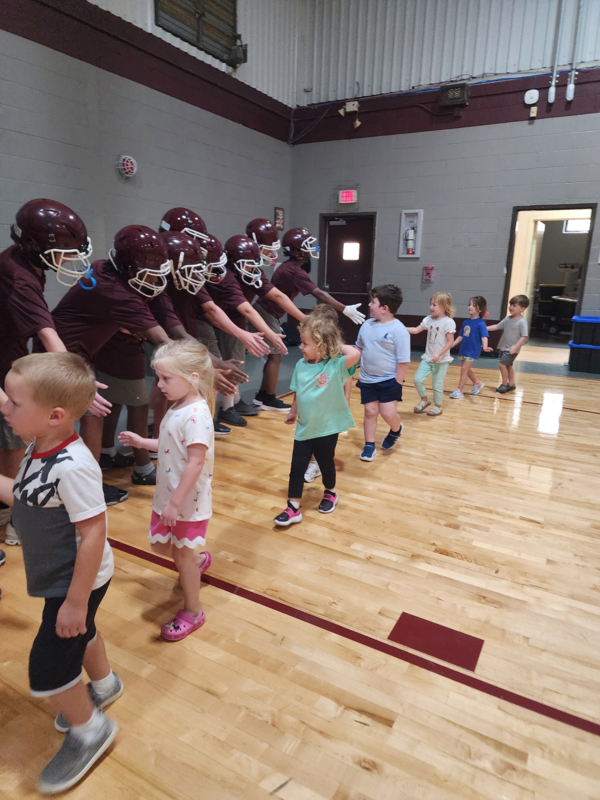 PreK students high fiving football players