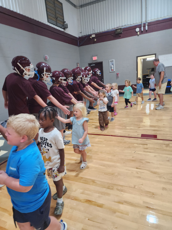 PreK students high fiving football players