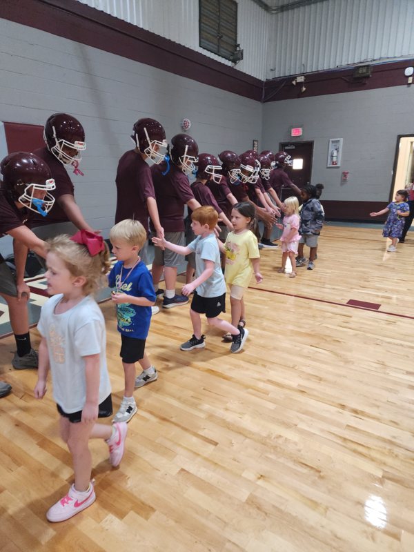 PreK students high fiving football players