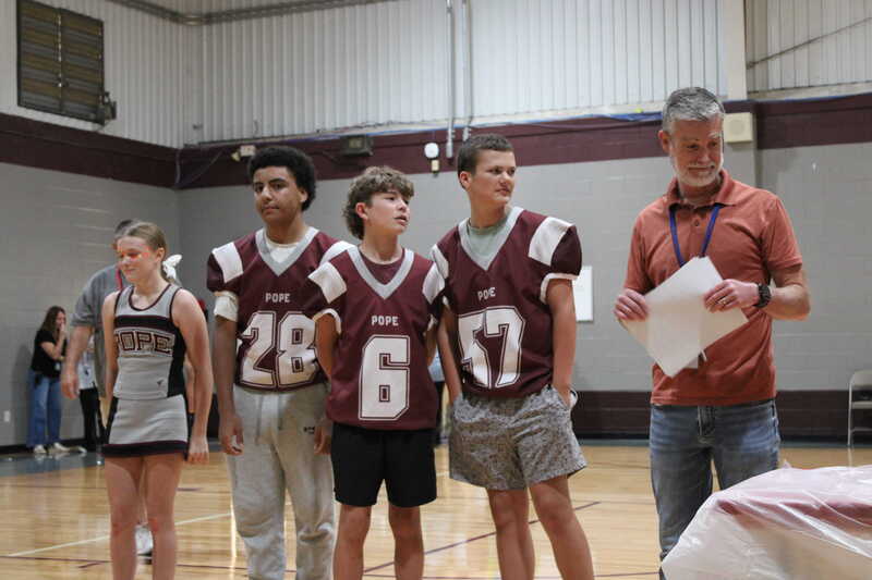 Junior high football players standing with teacher