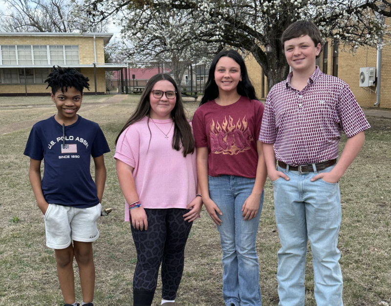 4 students standing in front of a curtain