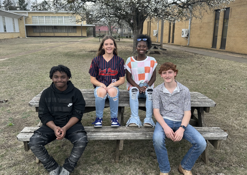 4 students standing in front of a curtain