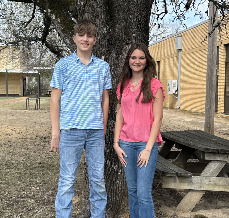 2 students standing in front of a curtain