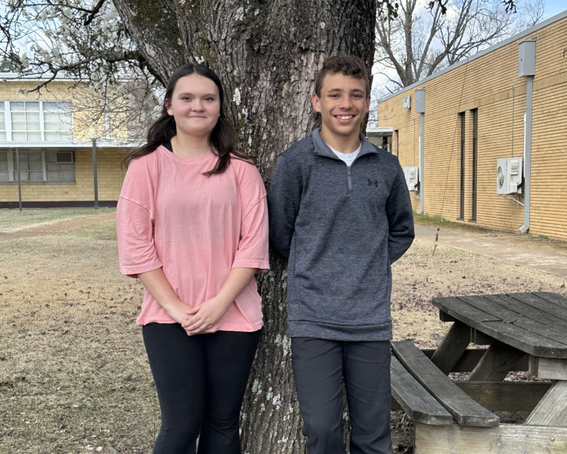 2 students standing in front of a curtain