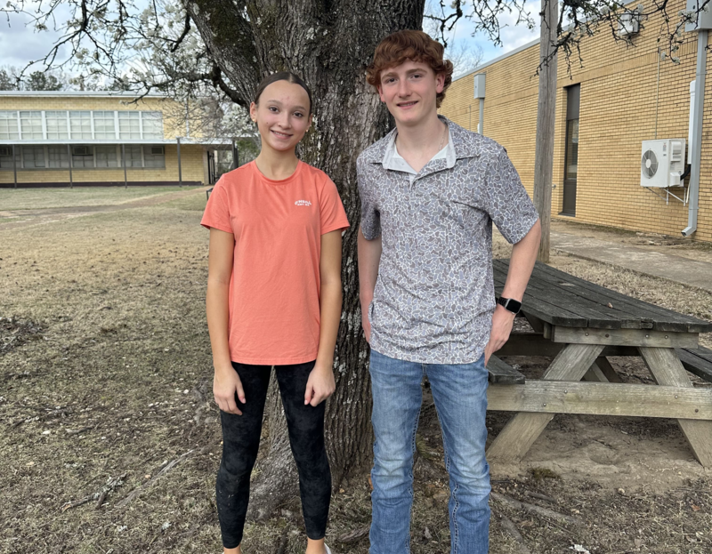2 students standing in front of a curtain