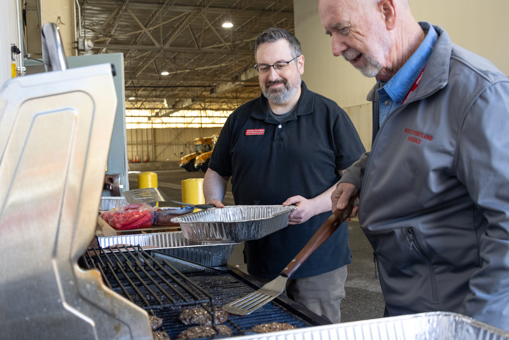School Board Member Adrian Dowling and Superintendent Entwistle cooking BBQ for Transportation Staff