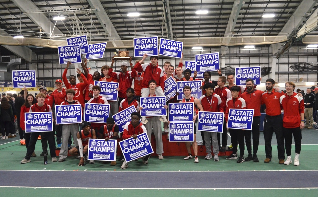 The 2025-26 Championship Boys Indoor South Portland High School Track Team holding 'State Champs' signs.