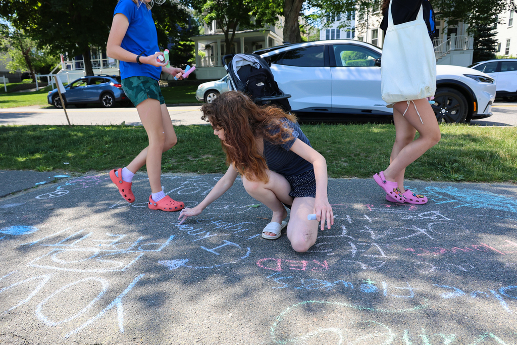 Students writing messages with chalk on the sidewalks at the Eastern Promenade