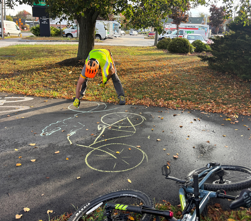 Thomas Hargrave, an education specialist with the Bicycle Coalition of Maine, draws with chalk at the launch event of the new South Portland byway. (Dana Richie/Staff Writer)