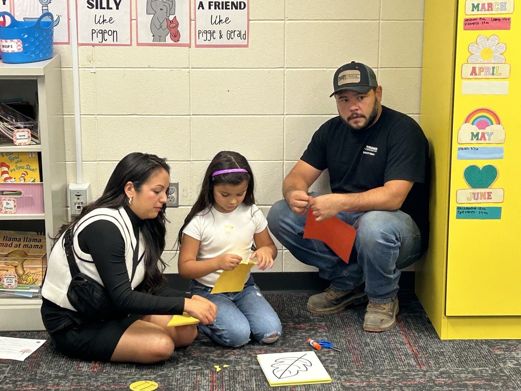 A student and her parents coloring a fall leaf