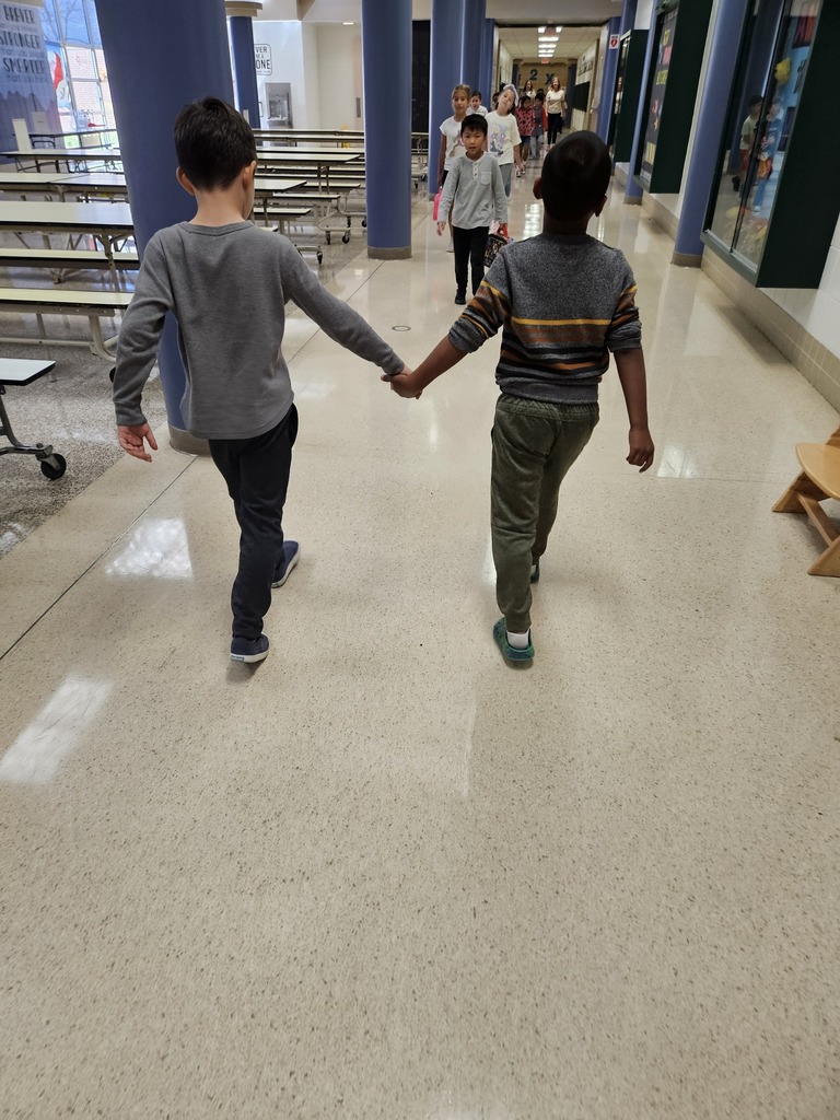 Two students holding hands walking down the hall