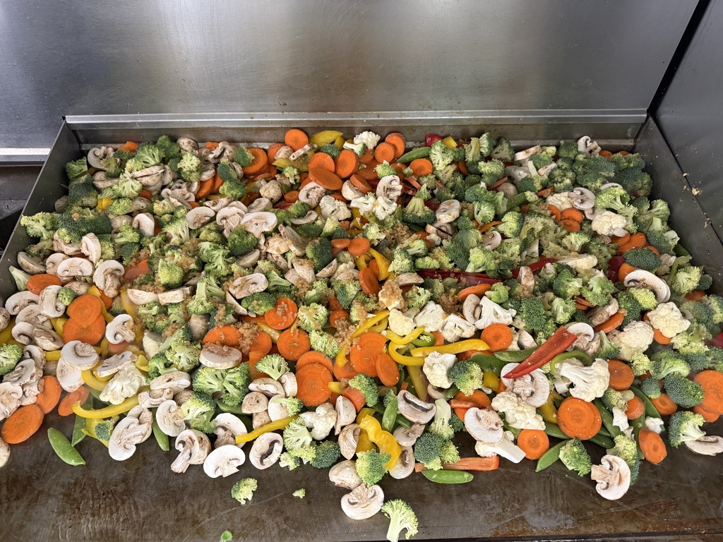 Veggies being cooked on the griddle.