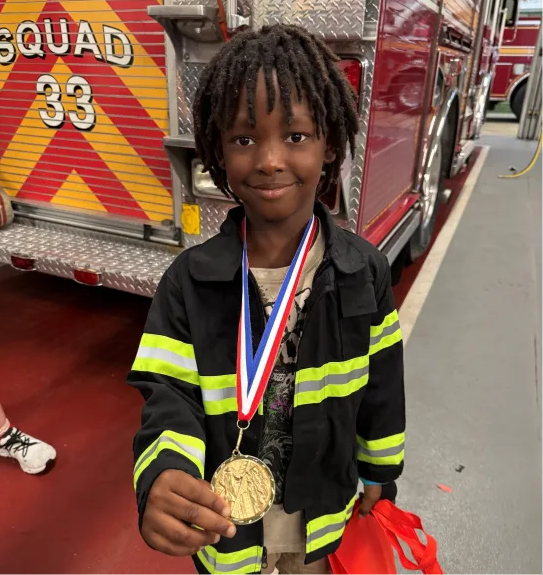 Kah'ir holding his medal at the fire department