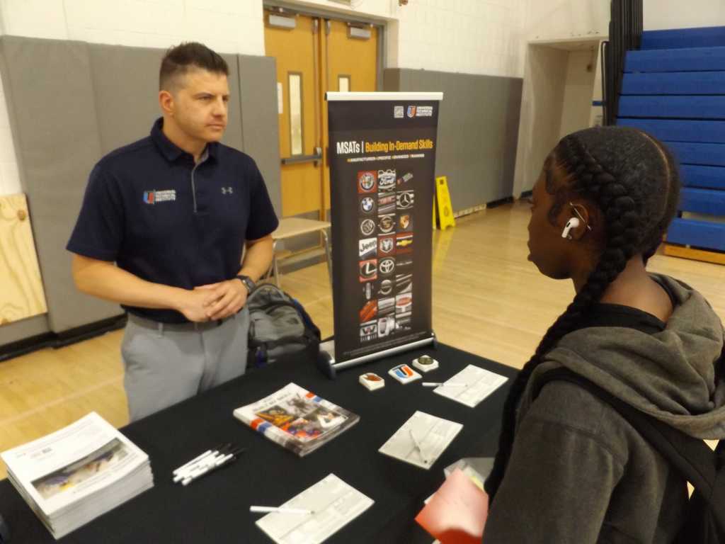 A student talks with a representative at a career training table.