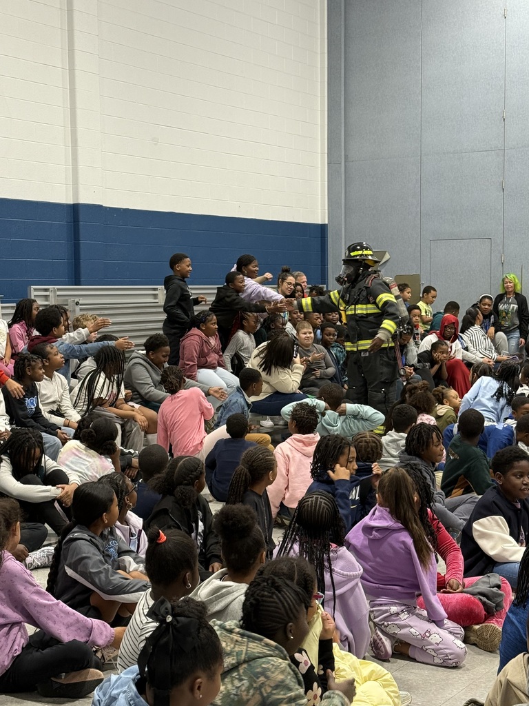 A firefighter in full gear walks through the crowd, greeting students during the assembly.