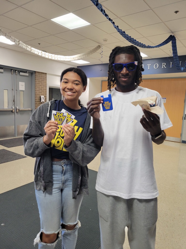 Two students stand together holding “PA Youth Vote” stickers and promotional items, smiling toward the camera.