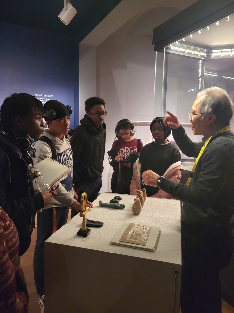 Students listening to museum volunteer share information