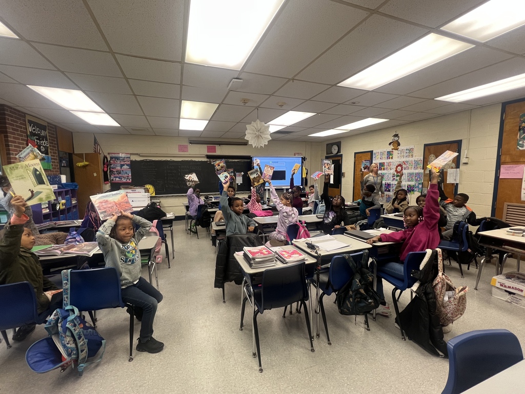 Students holding books in the air