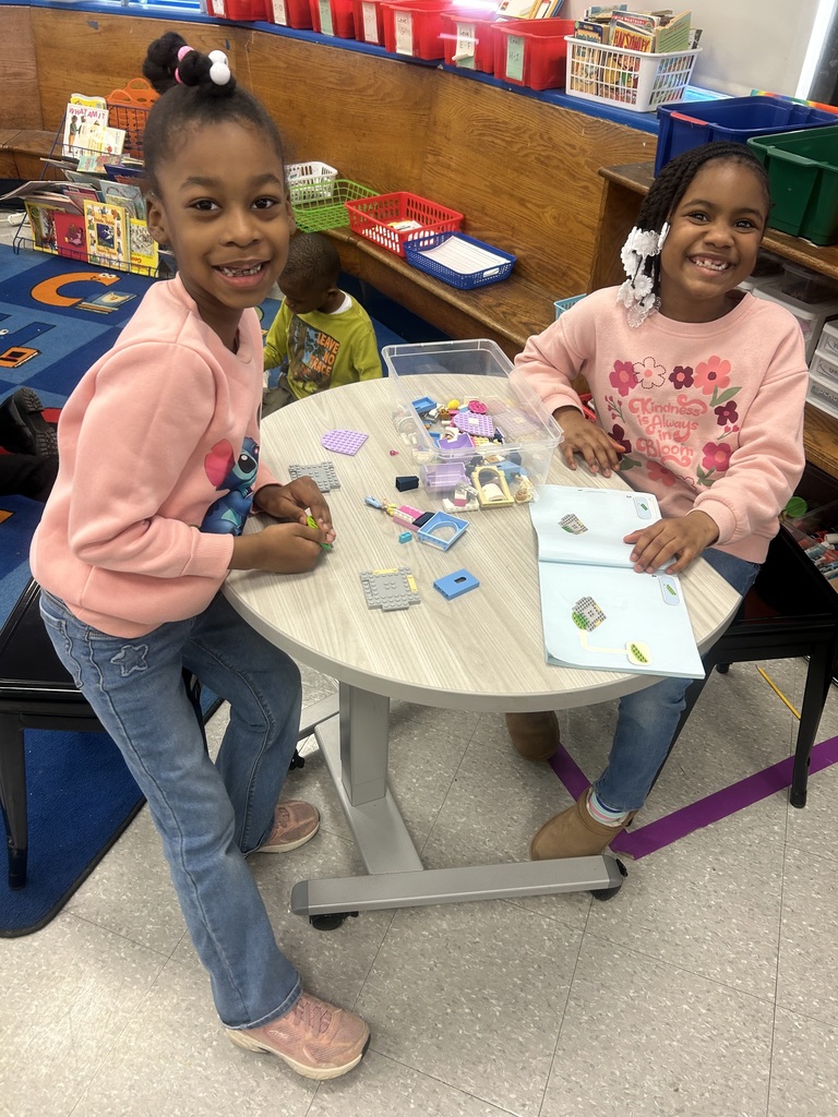 Two young girls engaged in a hands-on activity at a round table in a colorful classroom setting.