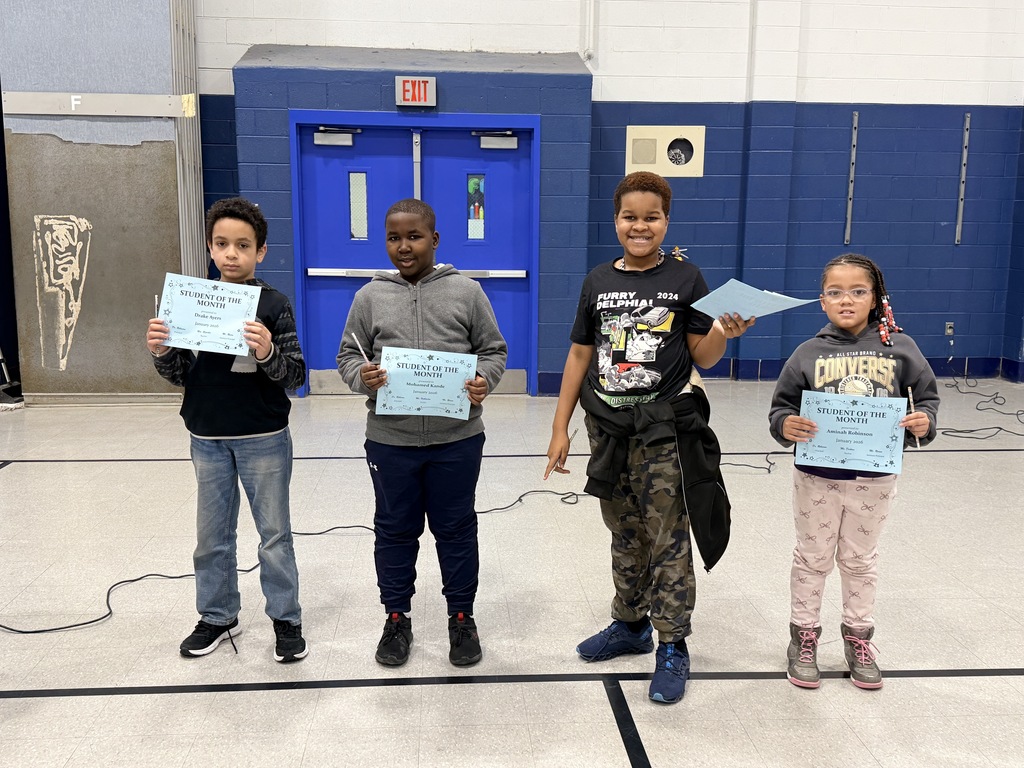Four students pose with “Student of the Month” certificates during an awards presentation.