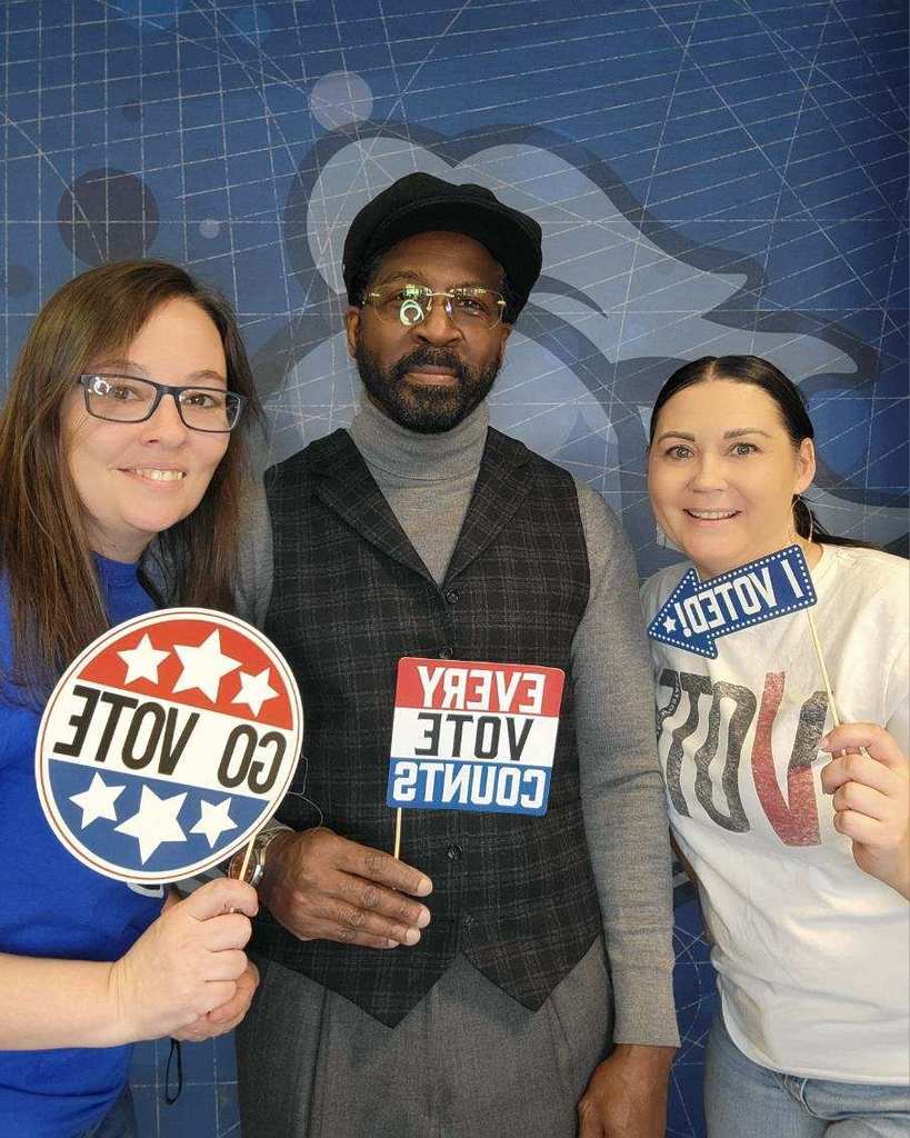 Three people holding voting-themed signs promoting participation and the importance of every vote in an election.