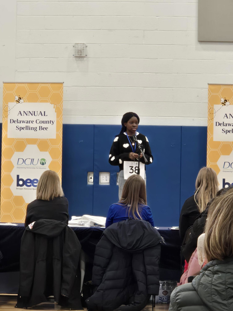 Contestant number 38 stands on stage at the Delaware County Annual Spelling Bee, facing judges seated in front of her.
