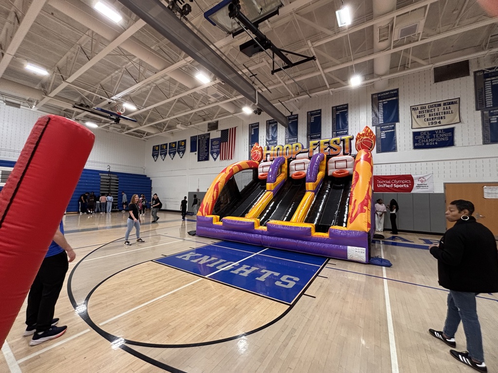 Large inflatable basketball challenge set up in a school gym with students and staff gathered nearby.