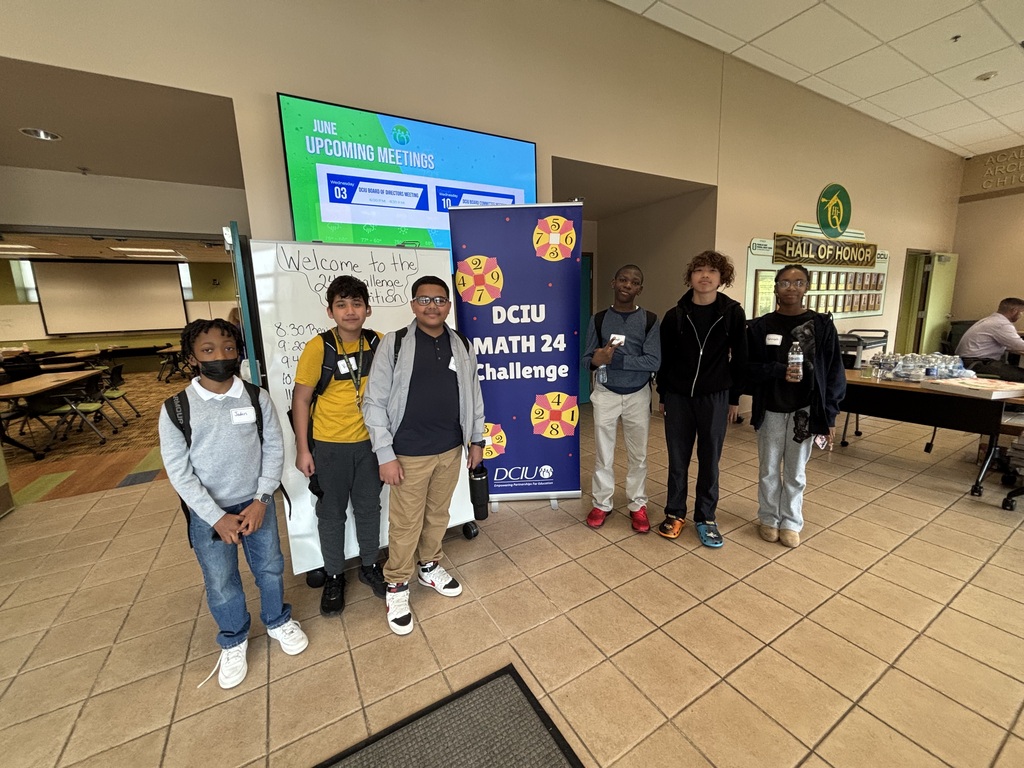 Six students pose at the DCIU Math 24 Challenge competition beside an event banner and welcome sign.